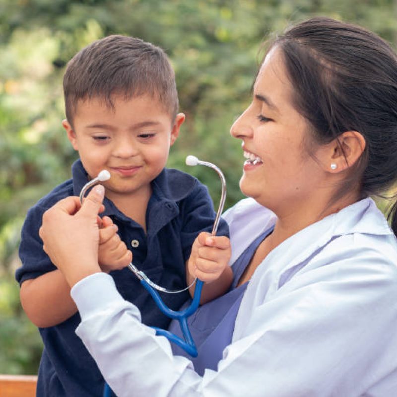 Portrait of a doctor and a child with Down syndrome smiling together.